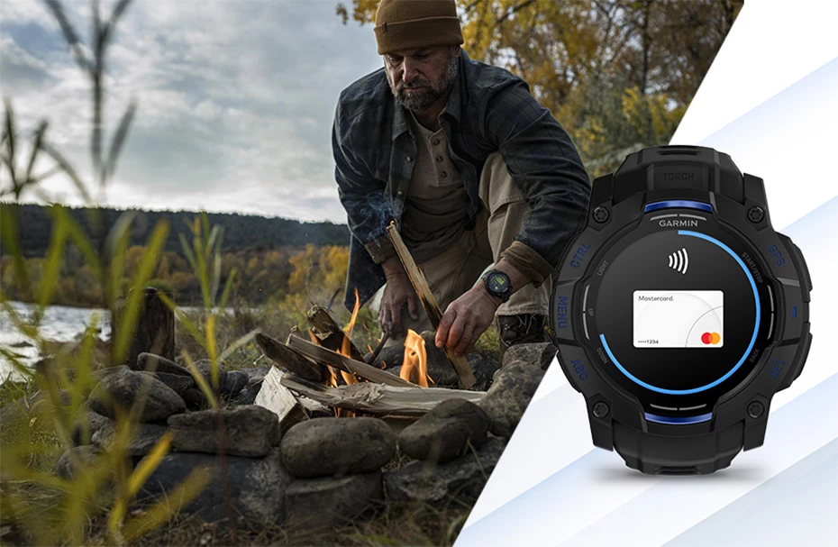 Чоловік розпалює багаття біля річки, поруч лежить годинник Garmin Instinct 3 з екраном безконтактної оплати Garmin Pay.
