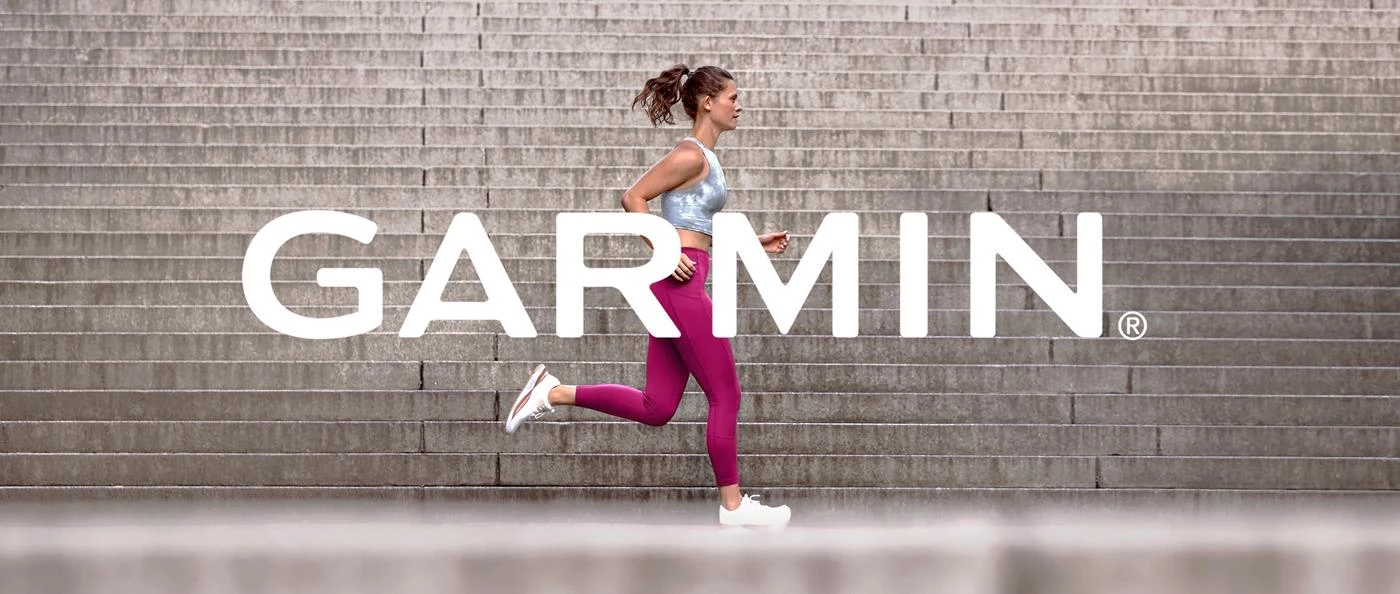 Жінка біжить сходами в спортивному одязі, на яких накладено великий логотип Garmin