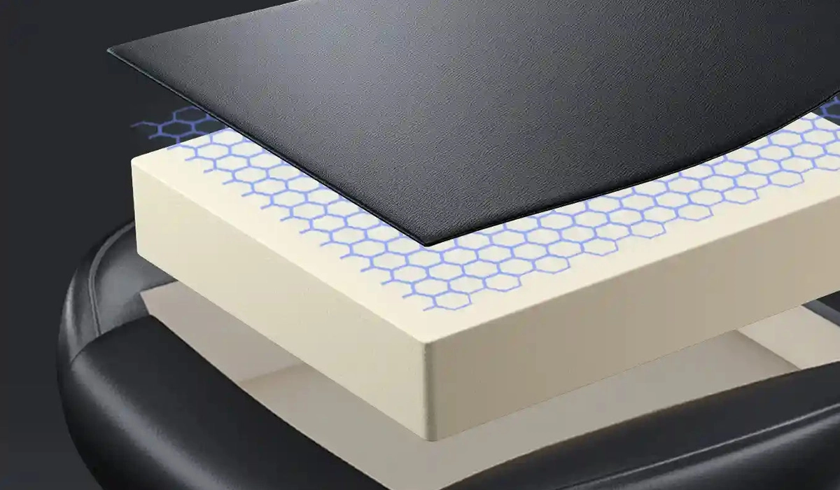 Widoczny jest przekrój fotela z warstwą pianki Memory Foam pokrytą siatką o wzorze plastra miodu oraz czarną tkaniną.