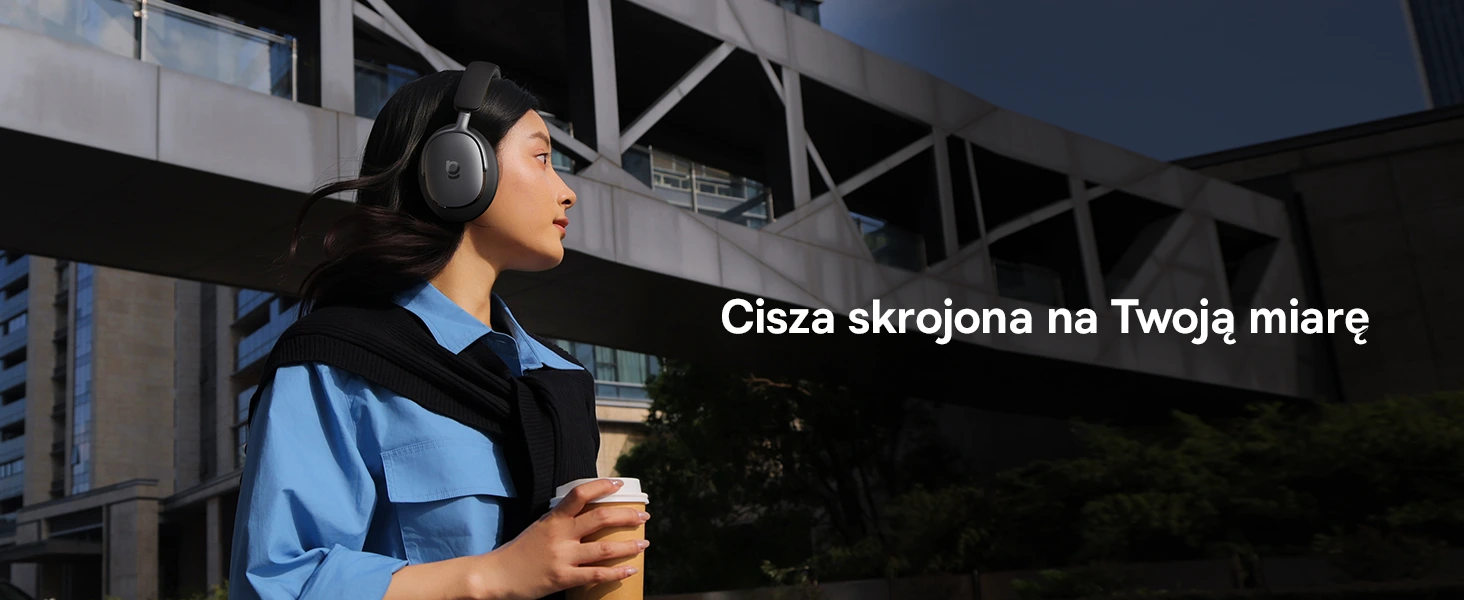 Жінка в чорних навушниках XH1 з чашкою кави в руці оглядає місто