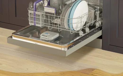 Відкрита посудомийна машина Beko з розлитою під нею водою.