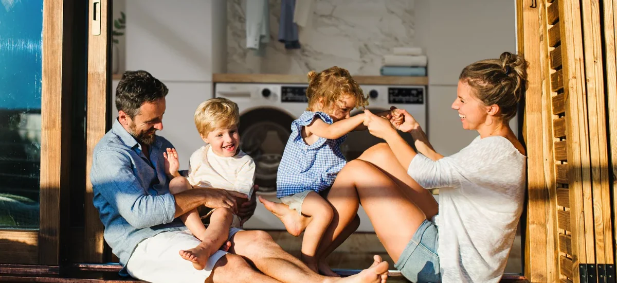 Родина грається на порозі свого будинку сонячного дня.