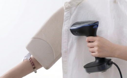 Людина прасує рукав сорочки портативним відпарювачем для одягу.