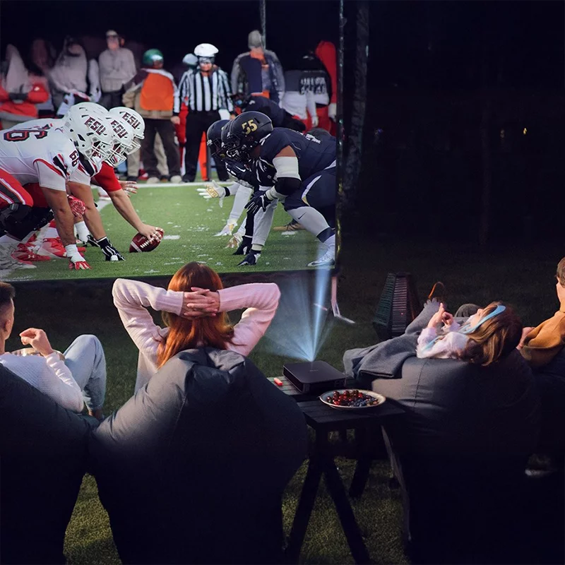 Група людей дивиться гру з американського футболу на великому екрані.