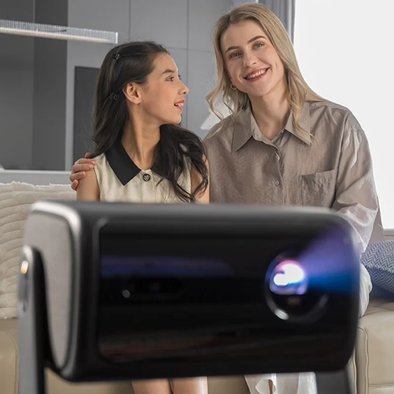 Мати та донька сидять на дивані та дивляться на проектор