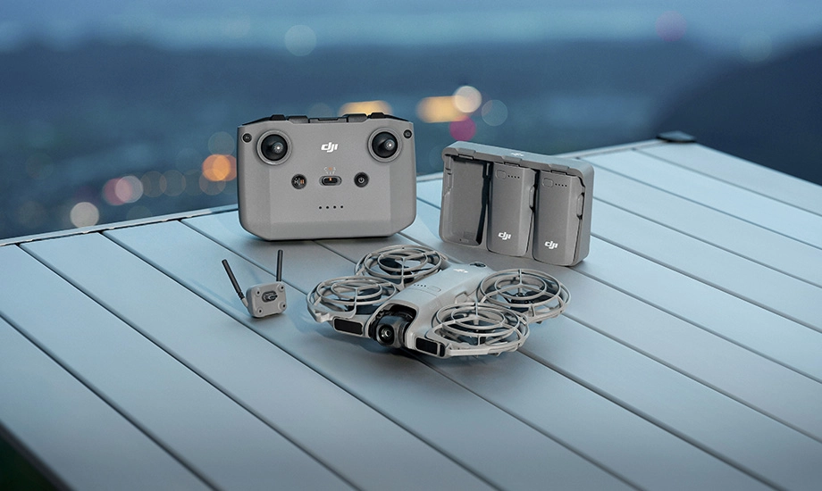 Комплект із дроном, контролером, двома батареями та камерою, що лежить на столі з краєвидом на задньому плані