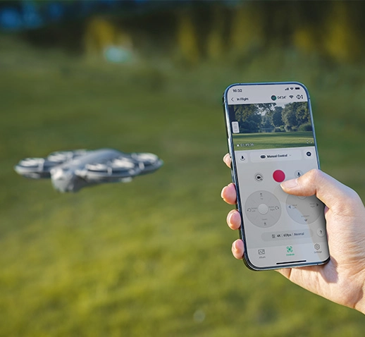 Людина тримає смартфон із додатком для керування дроном, що зависає на задньому плані