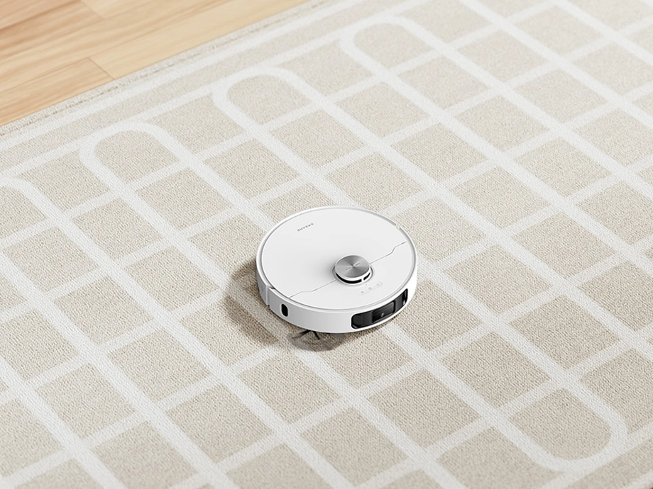 Робот пылесосит светлый ковер по определенной схеме.