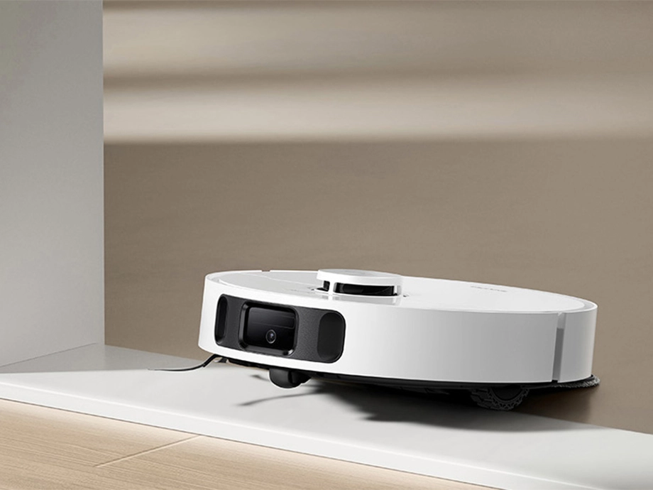 Робот въезжает на белый порог в светлой комнате.