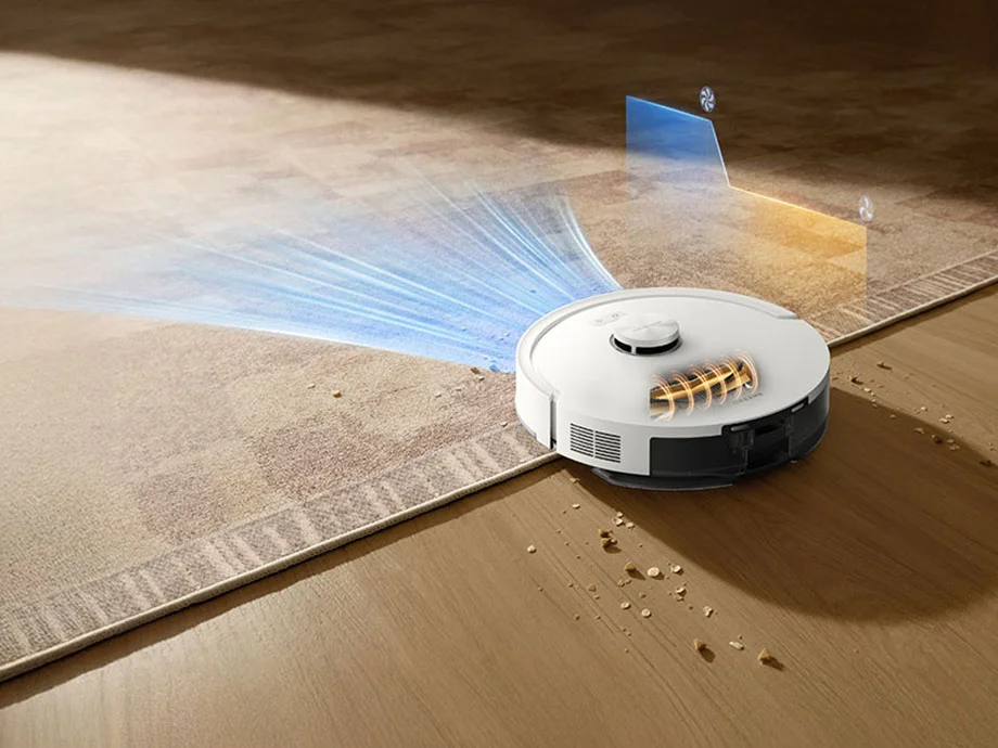 Білий робот-пилосос автоматично заїжджає на килим, збільшуючи силу всмоктування.