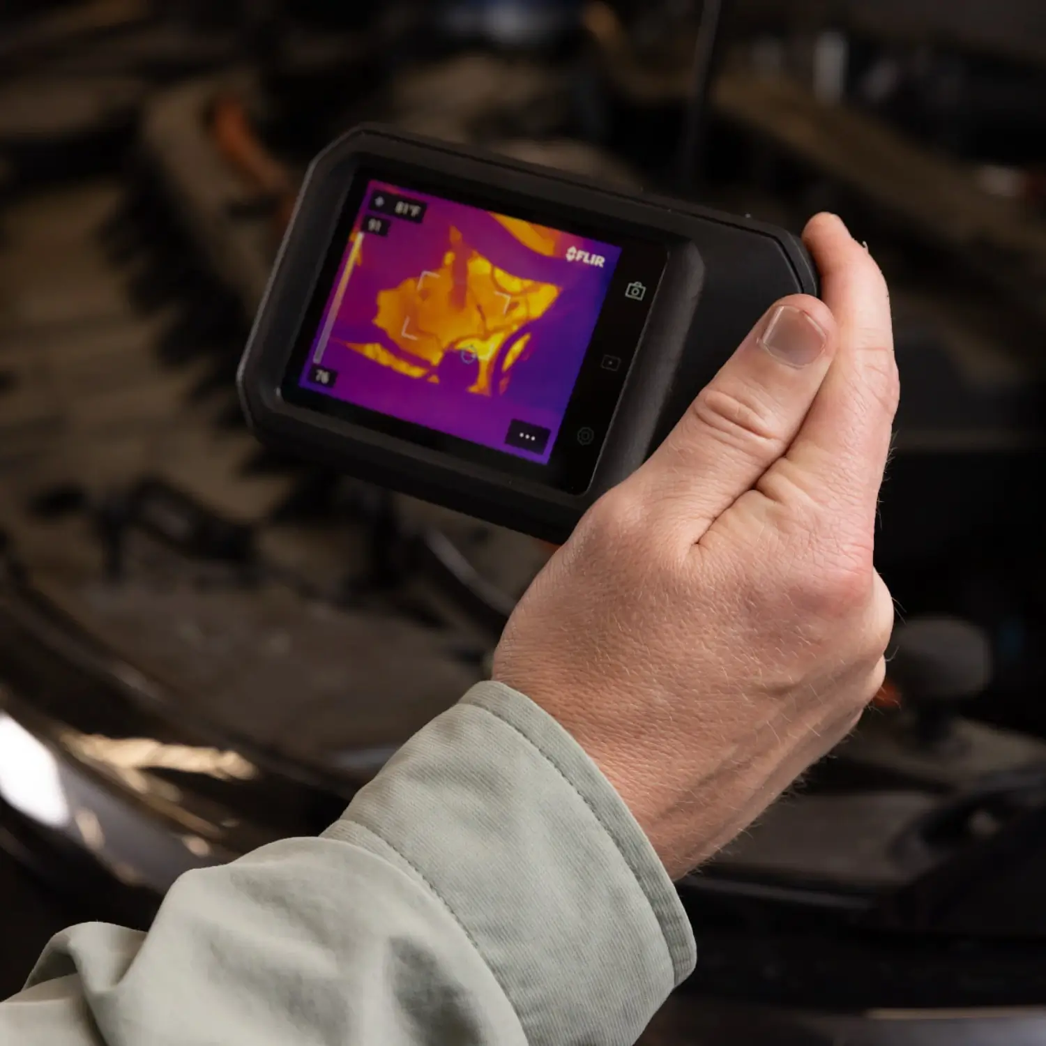 Тепловізійна камера FLIR C8, яку тримають у руці під час теплового аналізу автомобіля