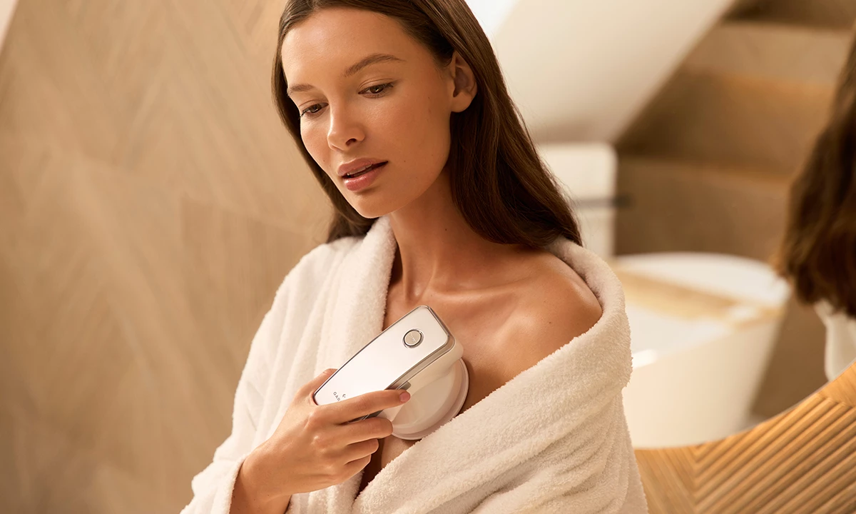 Жінка в білому халаті масажує декольте за допомогою пристрою Garett Beauty Cellu Body.
