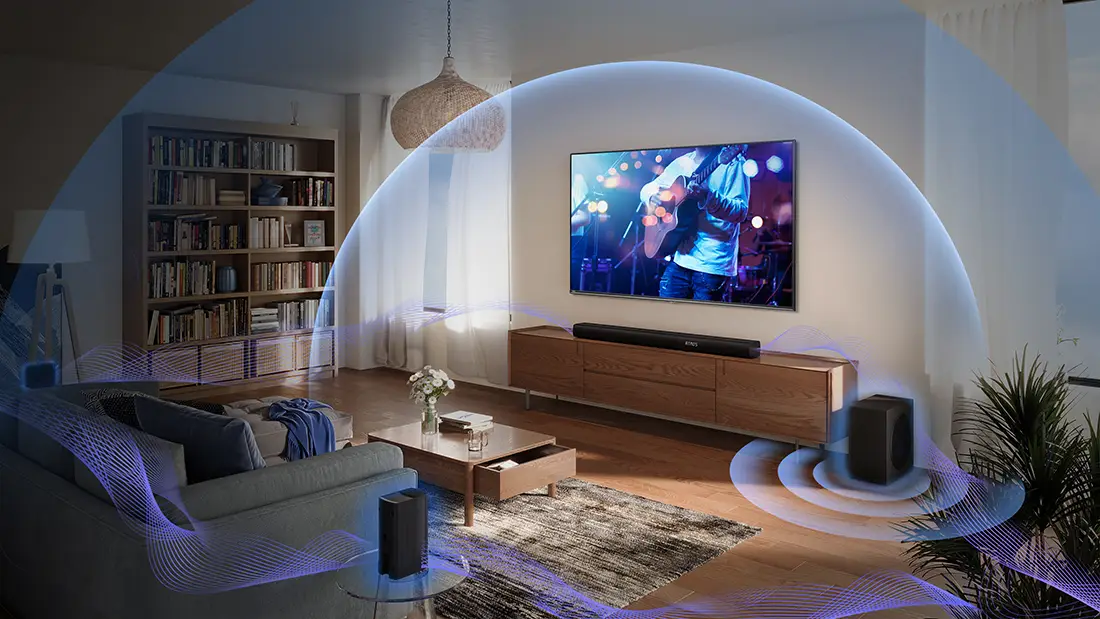 Вітальня з телевізором на стіні, саундбаром на шафі та колонками в кутах.