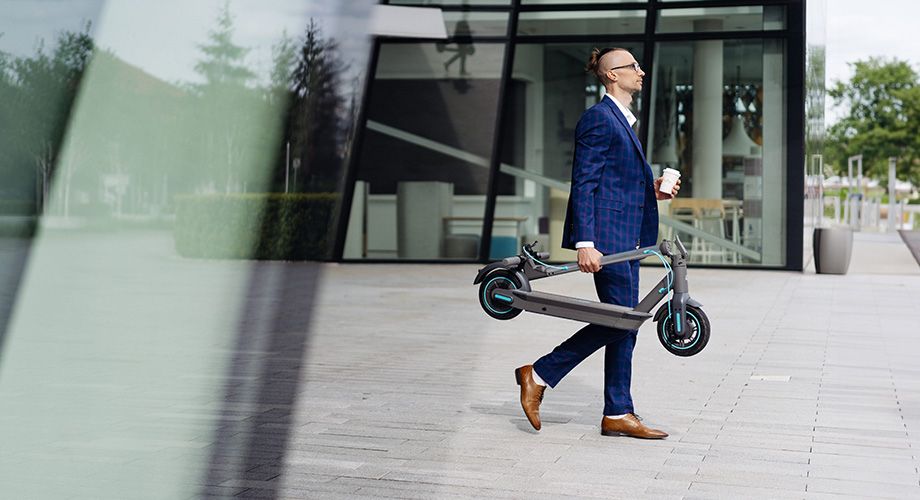 Дівчина несе складений самокат сходами.