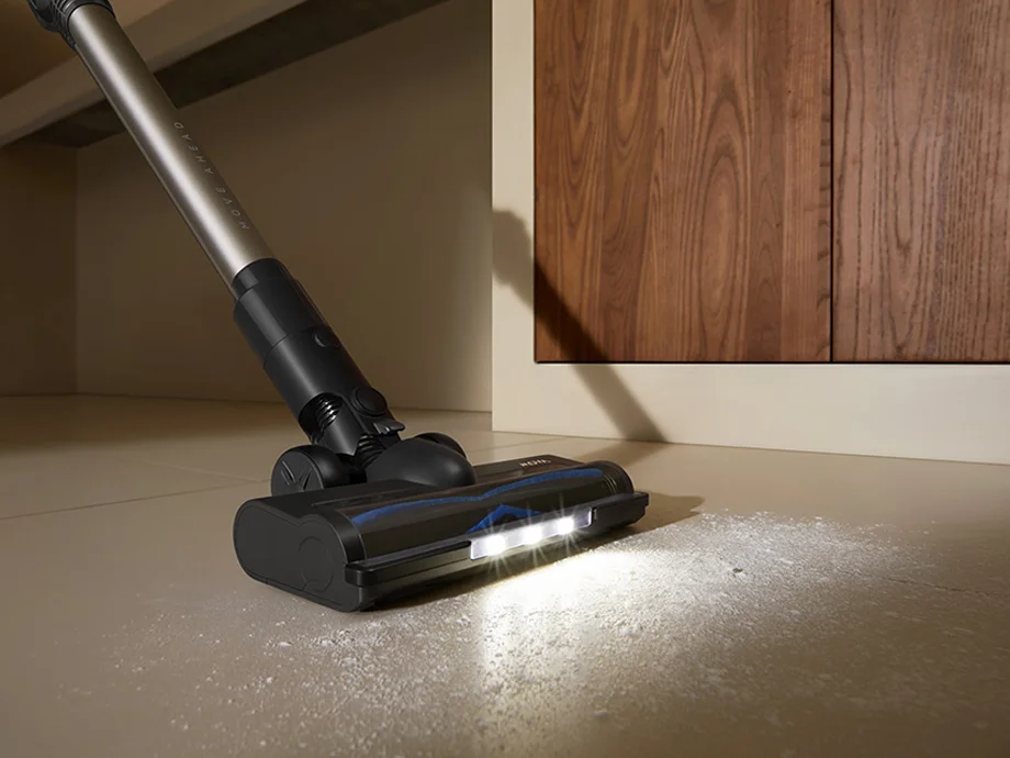 пилосос з підсвічуванням, що прибирає брудну підлогу поруч із шафою