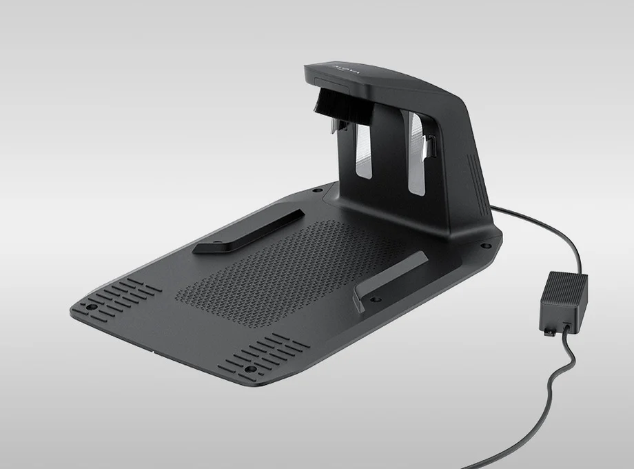 Чорна зарядна станція з кабелем для роботизованої газонокосарки на сірому фоні