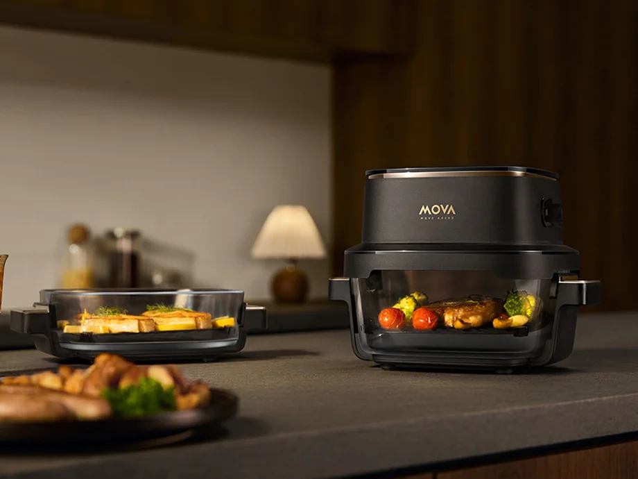 Чорна піч із прозорою камерою, в якій запікаються овочі та м'ясо, розміщена на кухонній стільниці