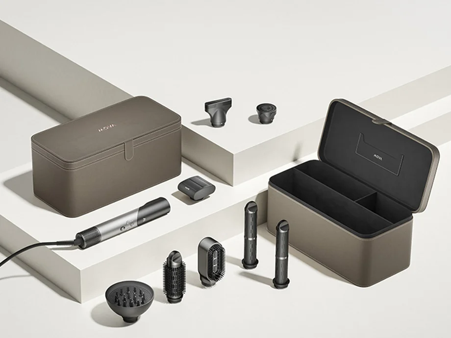 Набір для укладання волосся з різними насадками та двома футлярами на білому фоні з геометричним візерунком.