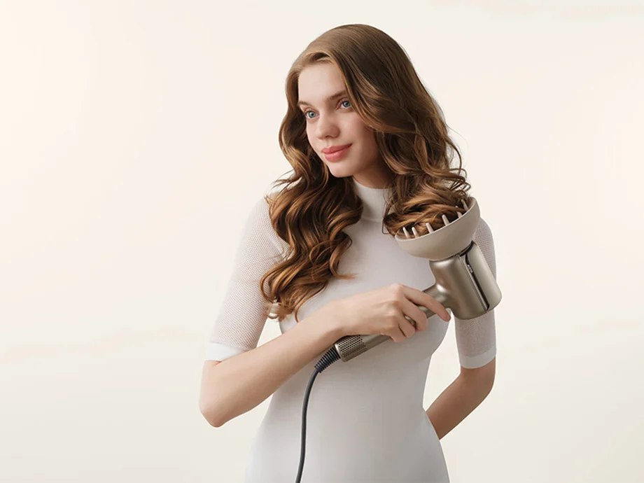Жінка використовує фен з дифузором, щоб укладати своє кучеряве волосся.