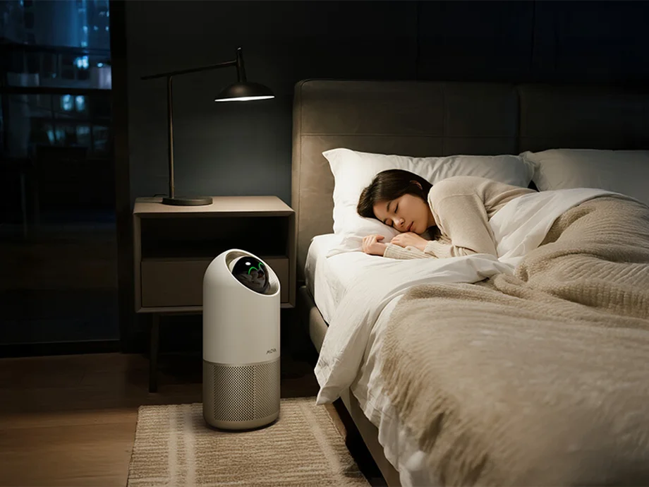 Жінка спить у своїй спальні з очищувачем повітря поруч з ліжком.