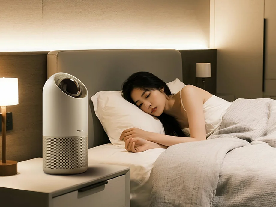 Жінка спить із увімкненим нічником та очищувачем повітря на столі поруч із нею.