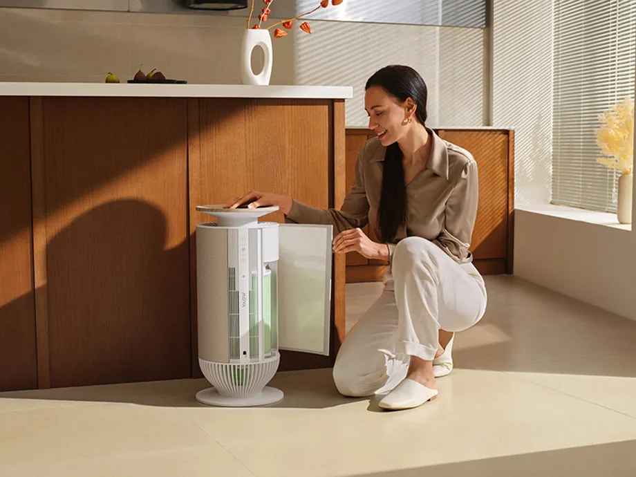 Жінка відкриває магнітну бічну панель очищувача повітря MOVA P10, демонструючи легкий доступ до заміни фільтра.