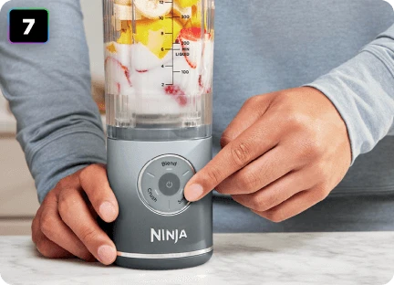 Чоловічі руки з вказівним пальцем на кнопці налаштувань блендера Ninja Blast Max BC251EU