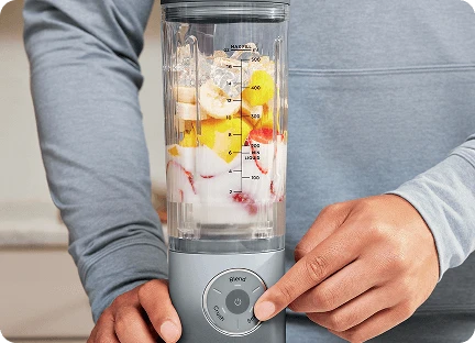 Чоловічі руки з вказівним пальцем на кнопці налаштувань блендера Ninja Blast Max BC251EU