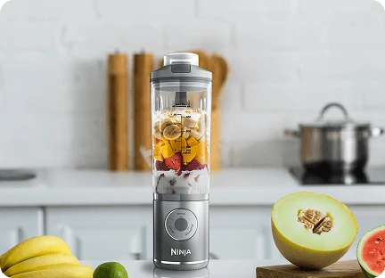 Блендер Ninja Blast Max BC251EU на кухонній стільниці, оточений фруктами, наповнений інгредієнтами