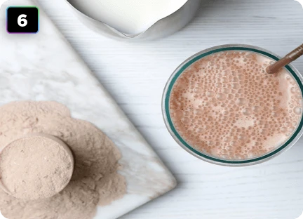 Світло-коричневий напій у склянці з порошком, розсипаним на прилавку поруч – вид зверху