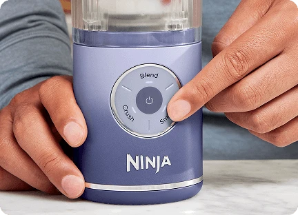 Крупний план рук із вказівним пальцем на кнопці налаштувань блендера Ninja Blast Max BC251EU