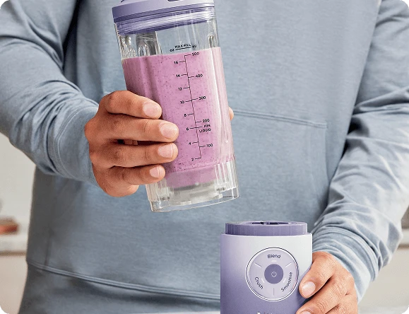 Руки виймають глечик, наповнений напоєм, з основи блендера