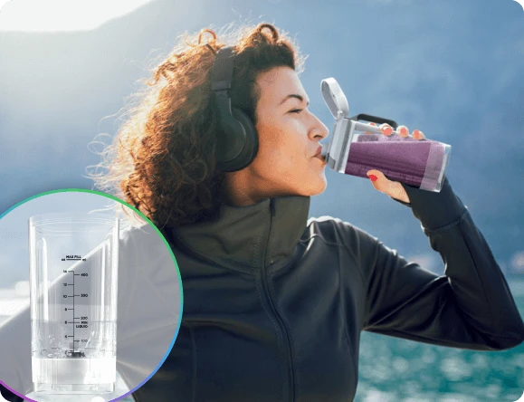 Жінка, оточена природою, п'є коктейль безпосередньо з блендера Ninja Blast Max BC251EU через кришку з носиком.