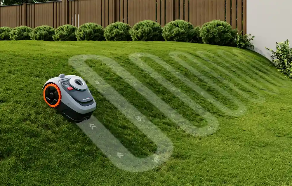 робот косить газон на пагорбі, з позначеним маршрутом скошування на газоні, навколишня територія - сад