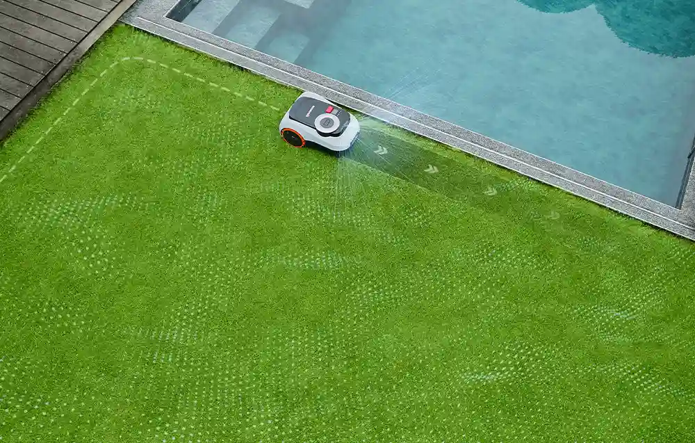 Вид зверху на робота, який косить траву вздовж бруківки басейну
