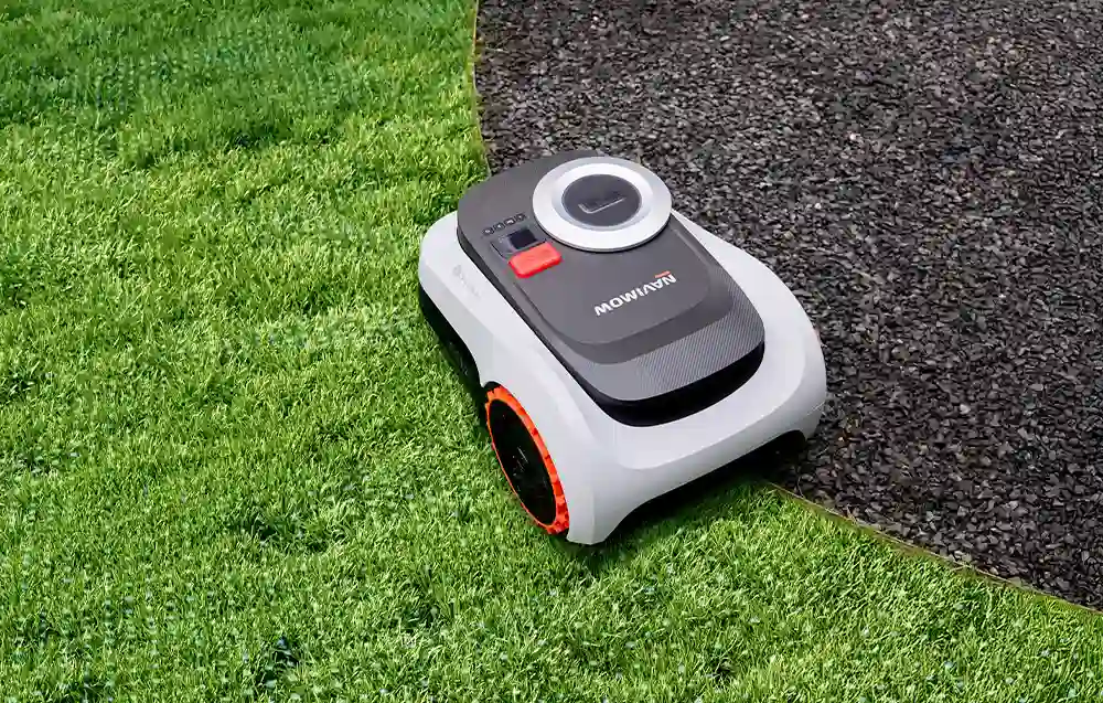 робот косить траву поруч із коричневою землею