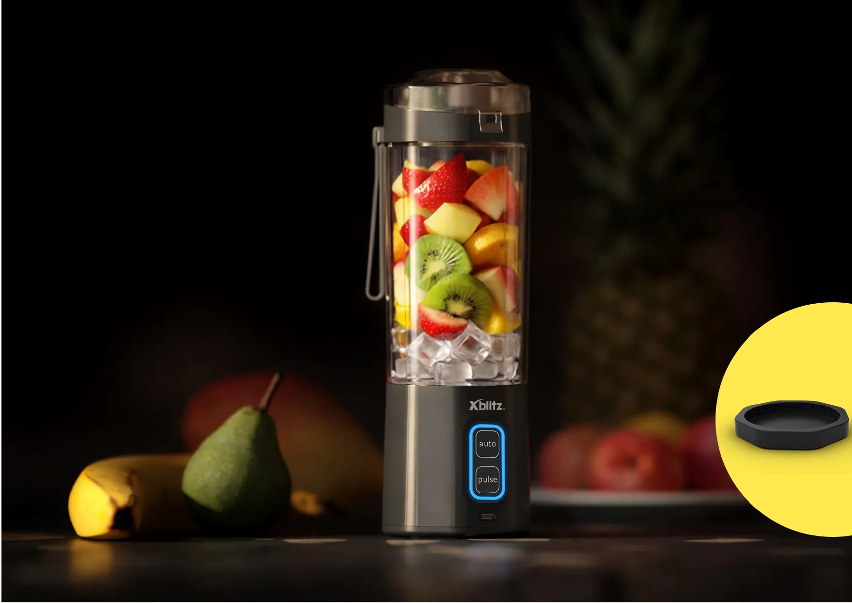 Blender z owocami na blacie, obok akcesorium, w tle owoce i ciemne tło kuchenne